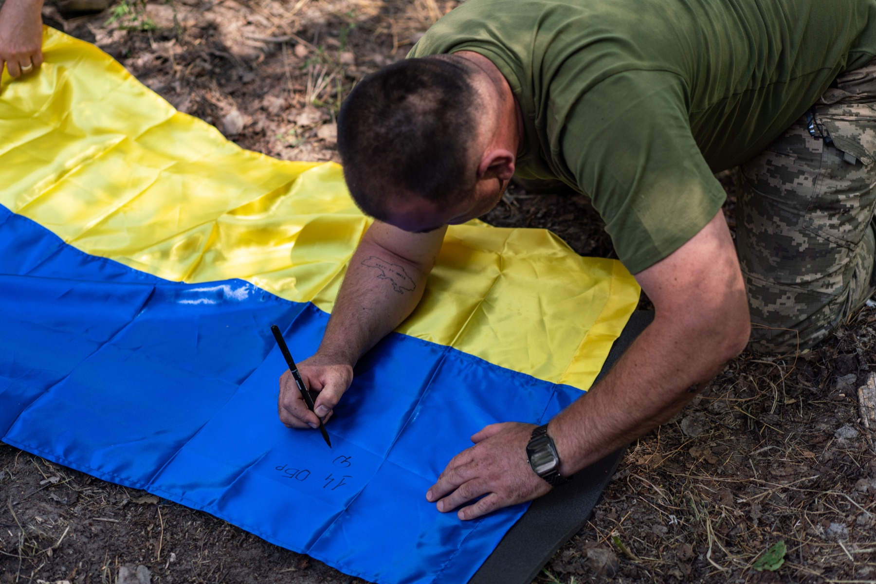 A participant signs a Ukrainian flag during an IGR field activity